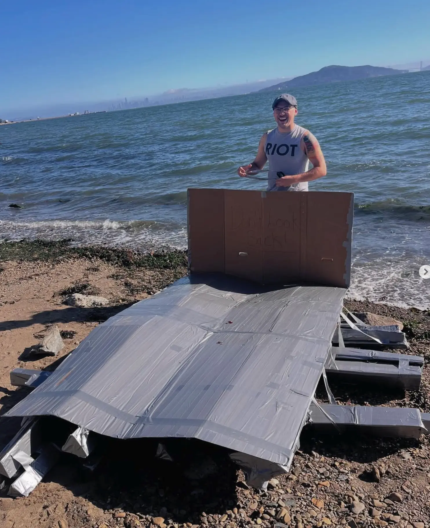Nick Holloway with his hand built cardboard boat on the bay